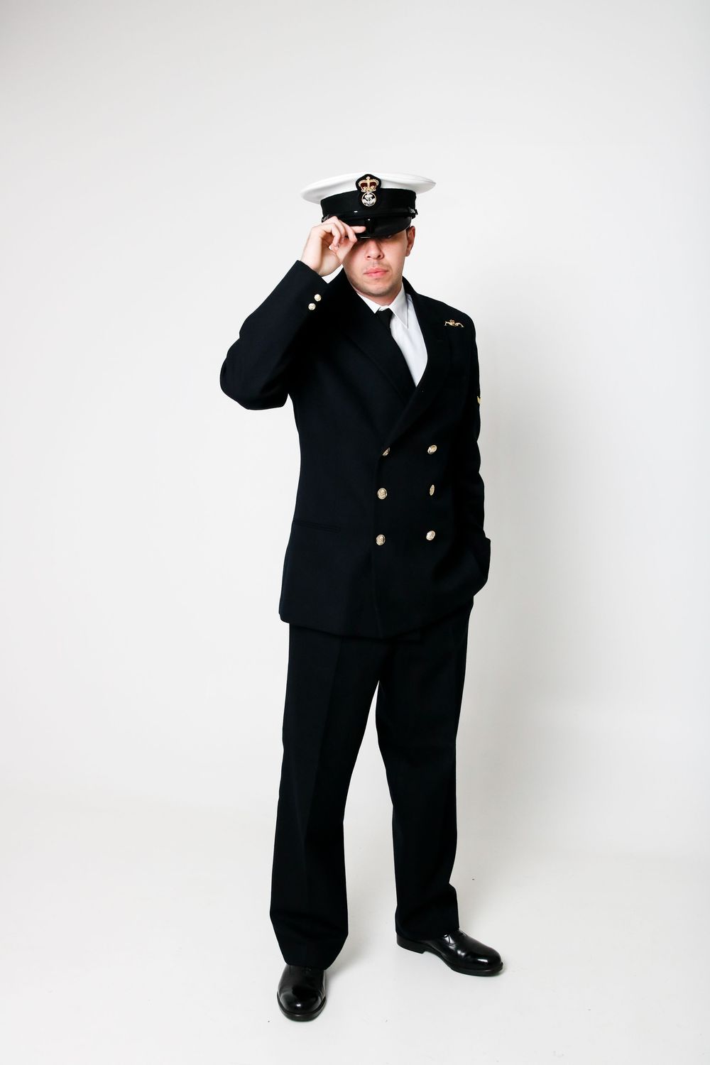 Figure in a formal naval uniform poses in different stances against white backdrop.