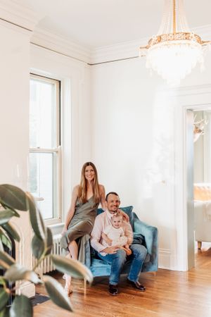 A family relaxes together in a bright white room with hardwood floors and an elegant crystal chandelier.