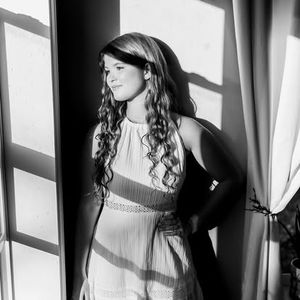 Black and white portrait series showing dramatic shadows and contrasts with long curly hair against a light background.