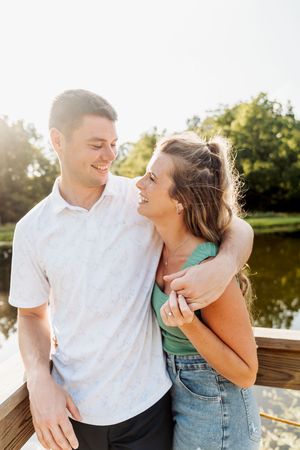 Happy couple shares tender moment together on wooden dock during golden sunset by lake.