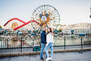Couple enjoying a romantic moment at Disney California Adventure Park with Mickey's Fun Wheel in the background.