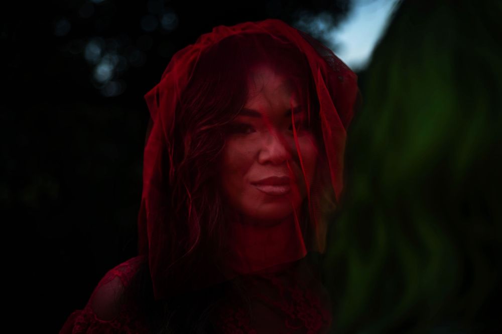 A woman's face behind a red veil.
