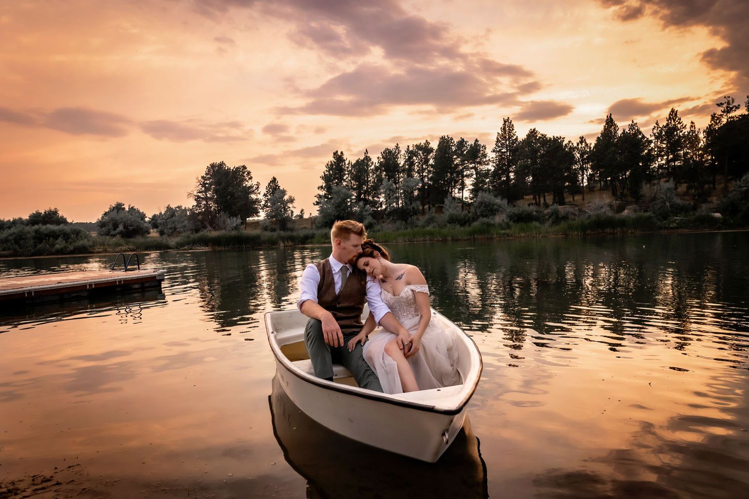 A romantic boat ride on a tranquil lake during a golden sunset with trees silhouetted in the background.