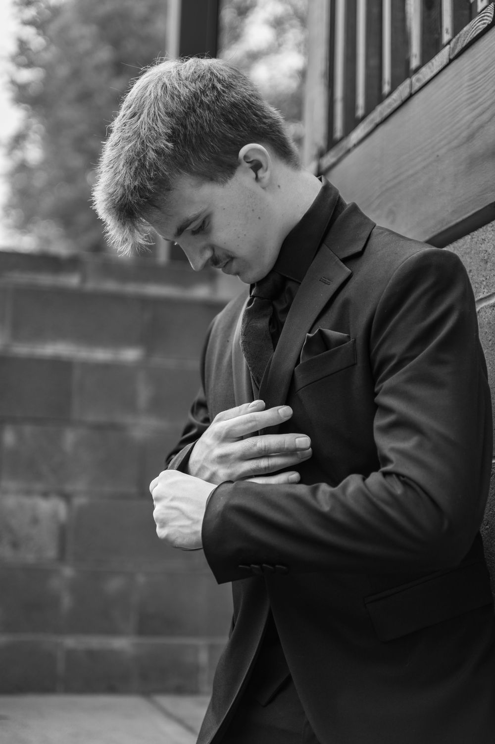 Black and white photo of a person in formal attire adjusting their tie.