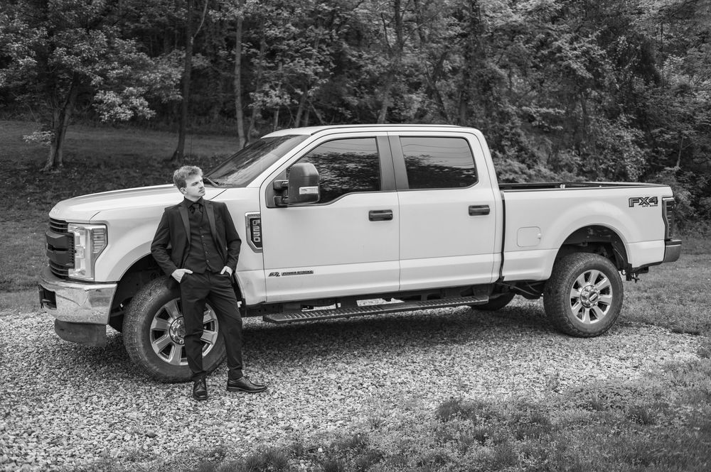 White Ford F-250 Super Duty truck with FX4 package on gravel driveway near wooded area.