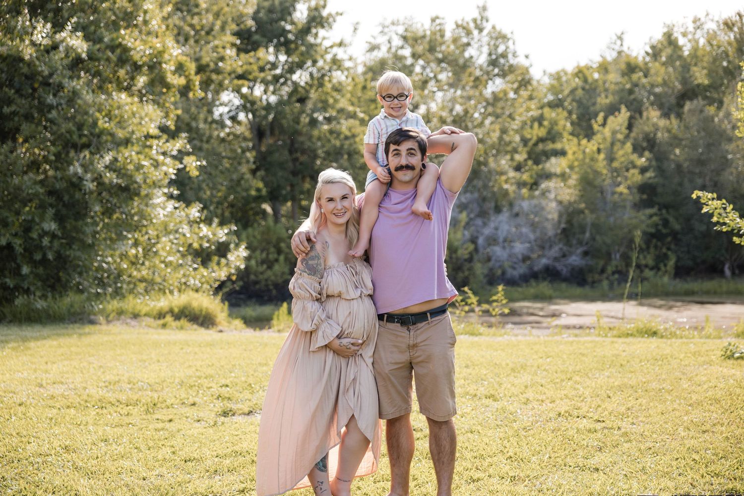 Maternity photo with expecting mom, fiancé, and son Elvis embracing and smiling together.