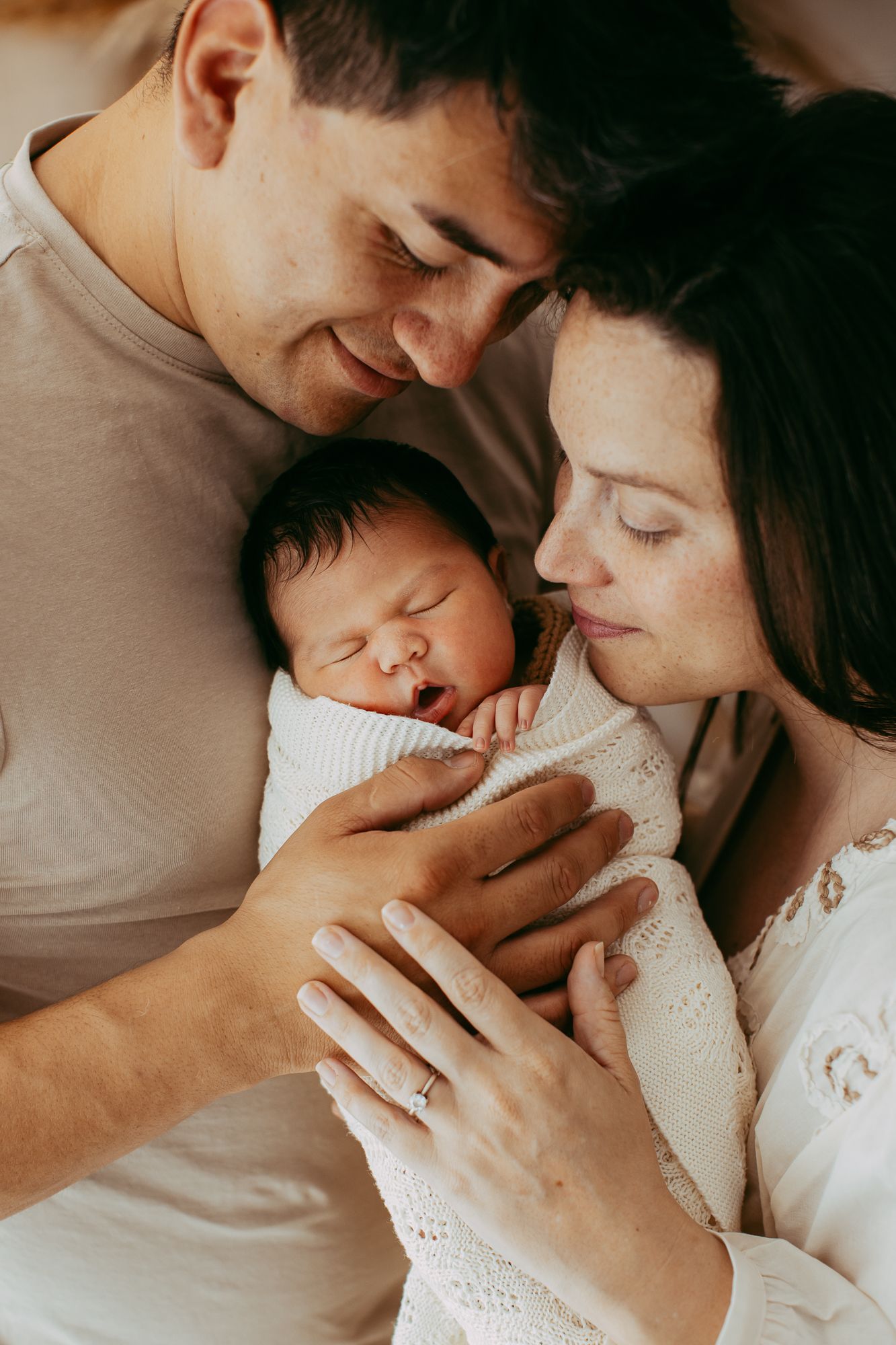 Intimate family moment with newborn baby in soft lighting.