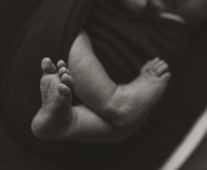 Black and white close-up of tiny newborn baby feet.