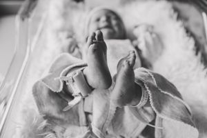 Black and white photo of newborn baby's feet against white fabric background.