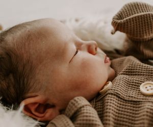 Close-up of sleeping infant in brown knit clothing.