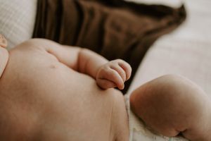 Close-up of baby's hand grasping against soft fabric.