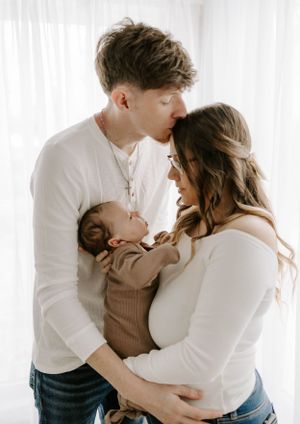 Tender family moment with newborn in brown sweater.