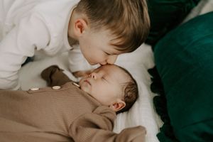 Sweet moment between two children as one gives the other a gentle kiss on the forehead.