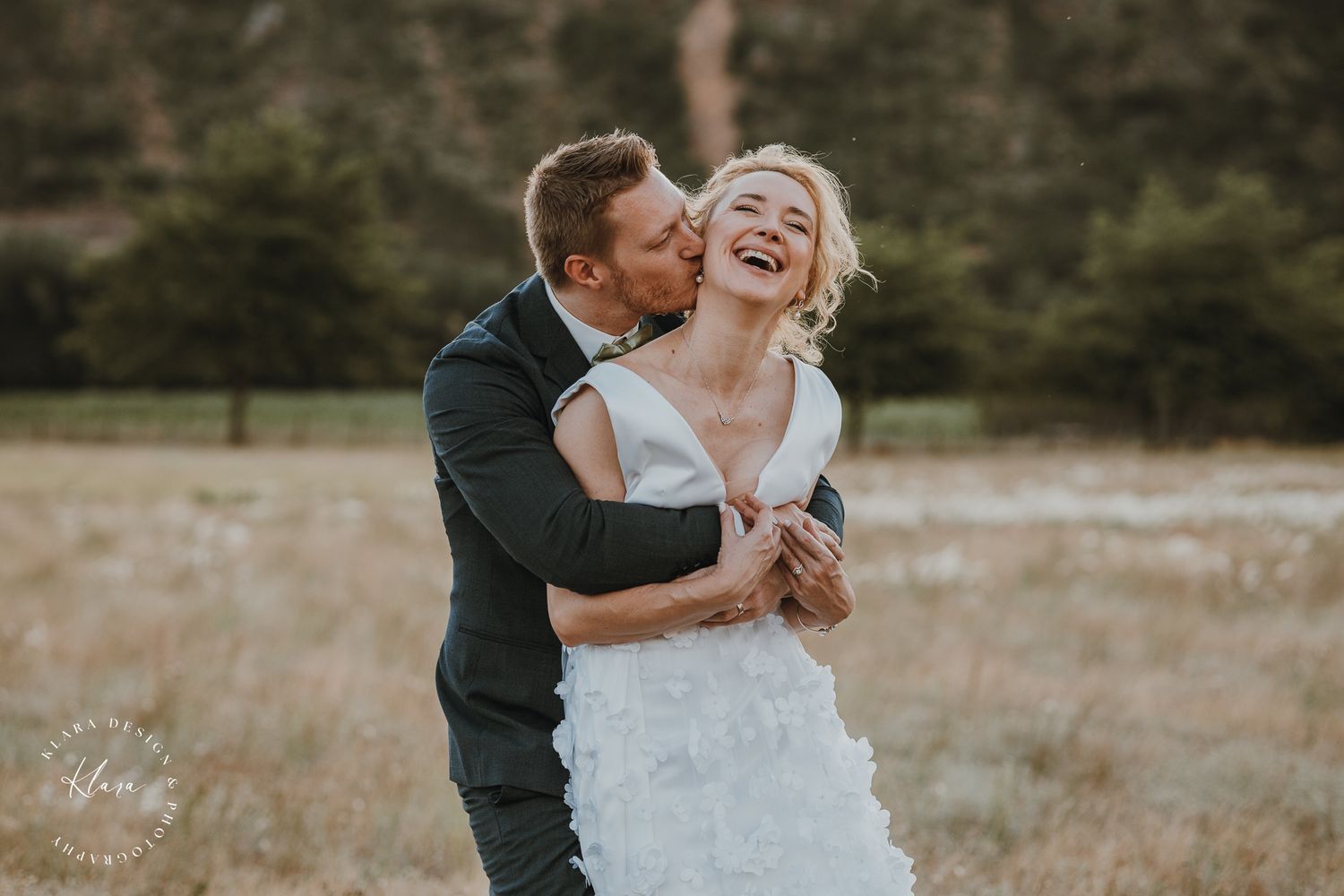 Romantic couple in wedding attire sharing a tender moment on a mountain path.