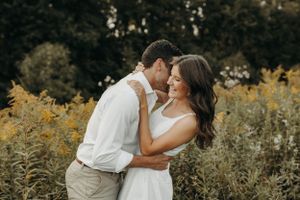 Romantic couple embracing in a field of yellow wildflowers during golden hour.