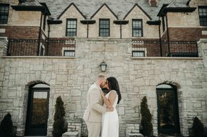 Couple sharing a romantic moment in front of a stone building on their wedding day.