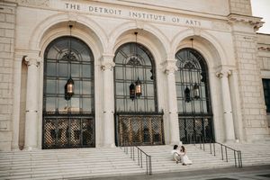 Couple sitting on steps of Detroit Institute of Arts neoclassical building.