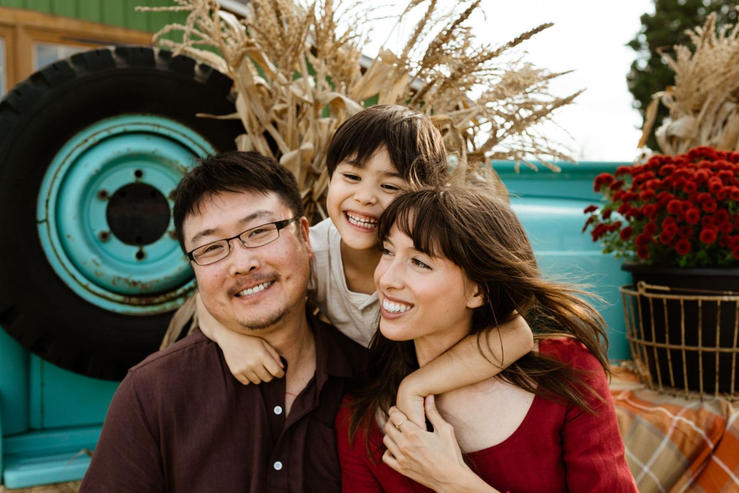 A happy family moment captured in front of a turquoise vintage truck with dried wheat decor.