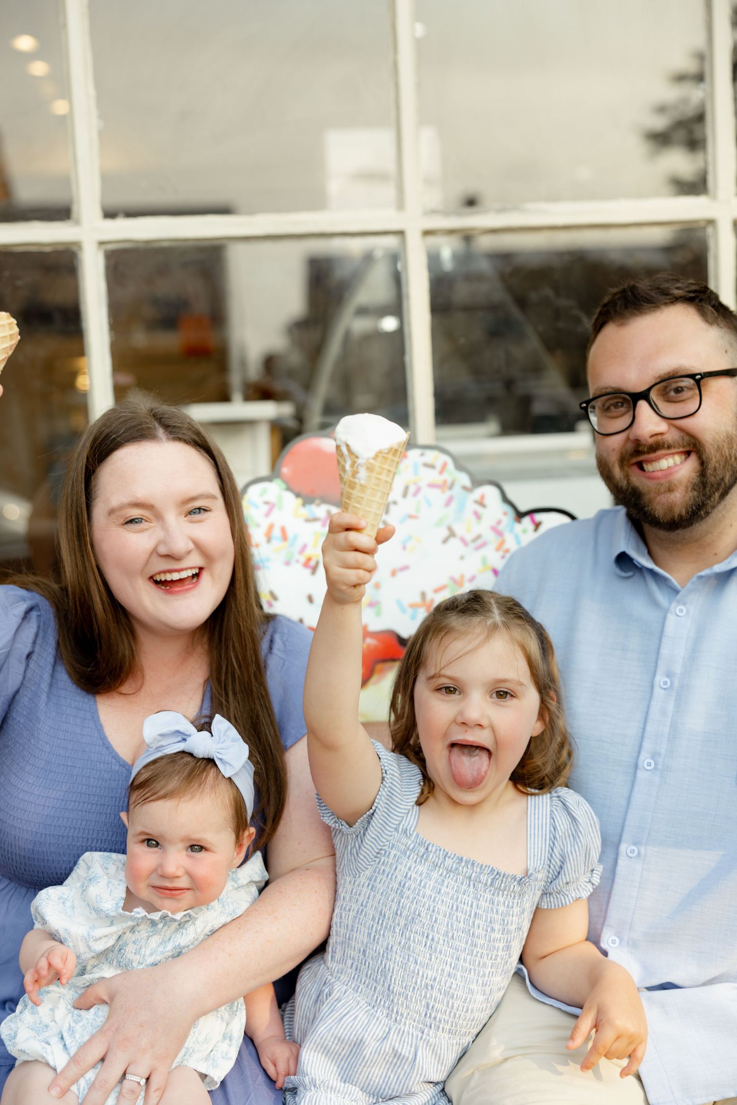 A joyful family shares a fun moment together in matching blue and white outfits while holding ice cream cones.
