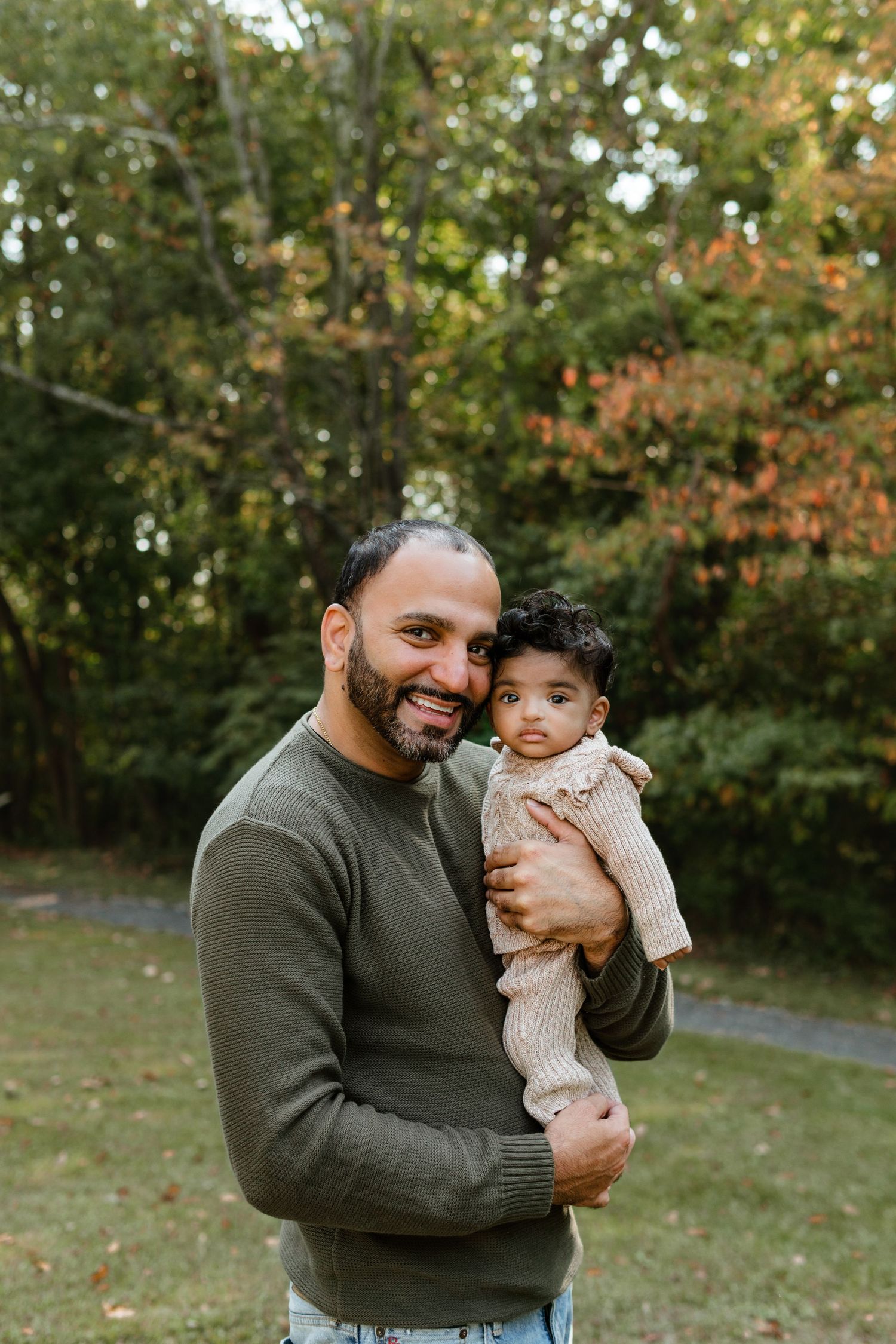 Dad in a green sweater holding baby during fall mini sessions at Barclay Farmstead in Cherry Hill, NJ.