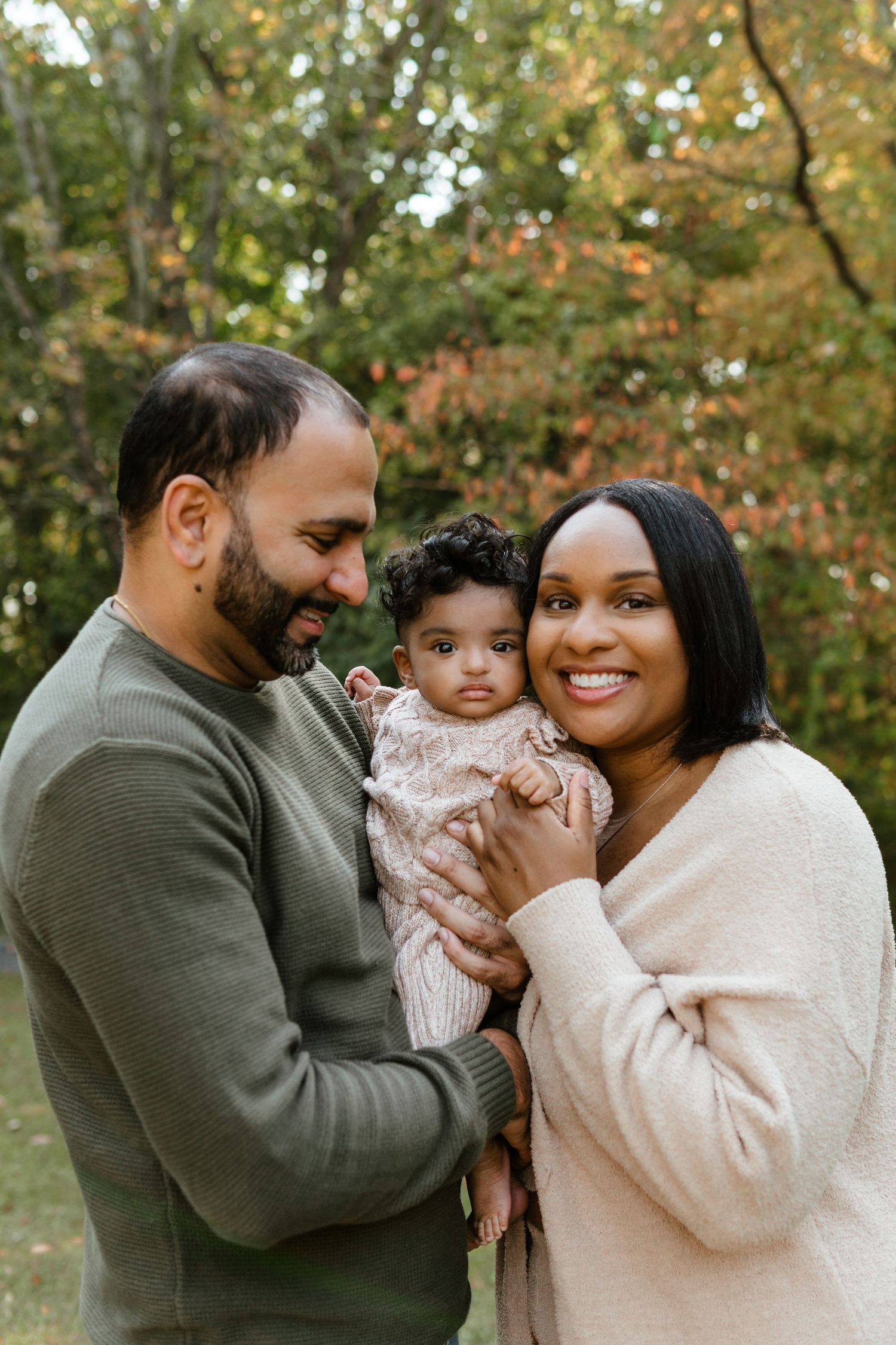 A family shares a tender moment together outdoors during autumn with colorful fall foliage at Barclay Farmstead.