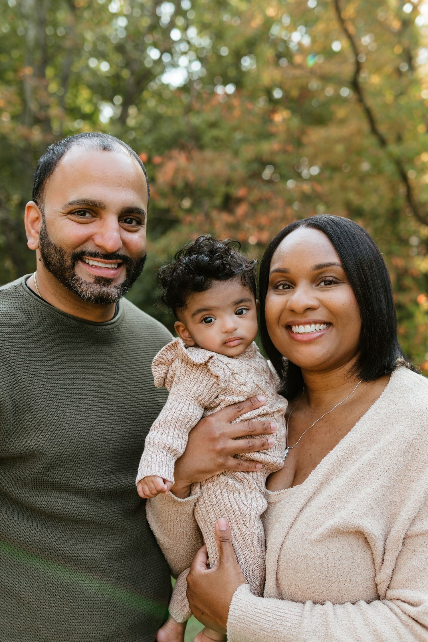 A family of three smiling looking into the camera at a fall mini session with Cherry Hill family photographer at Barclay Farmstead.