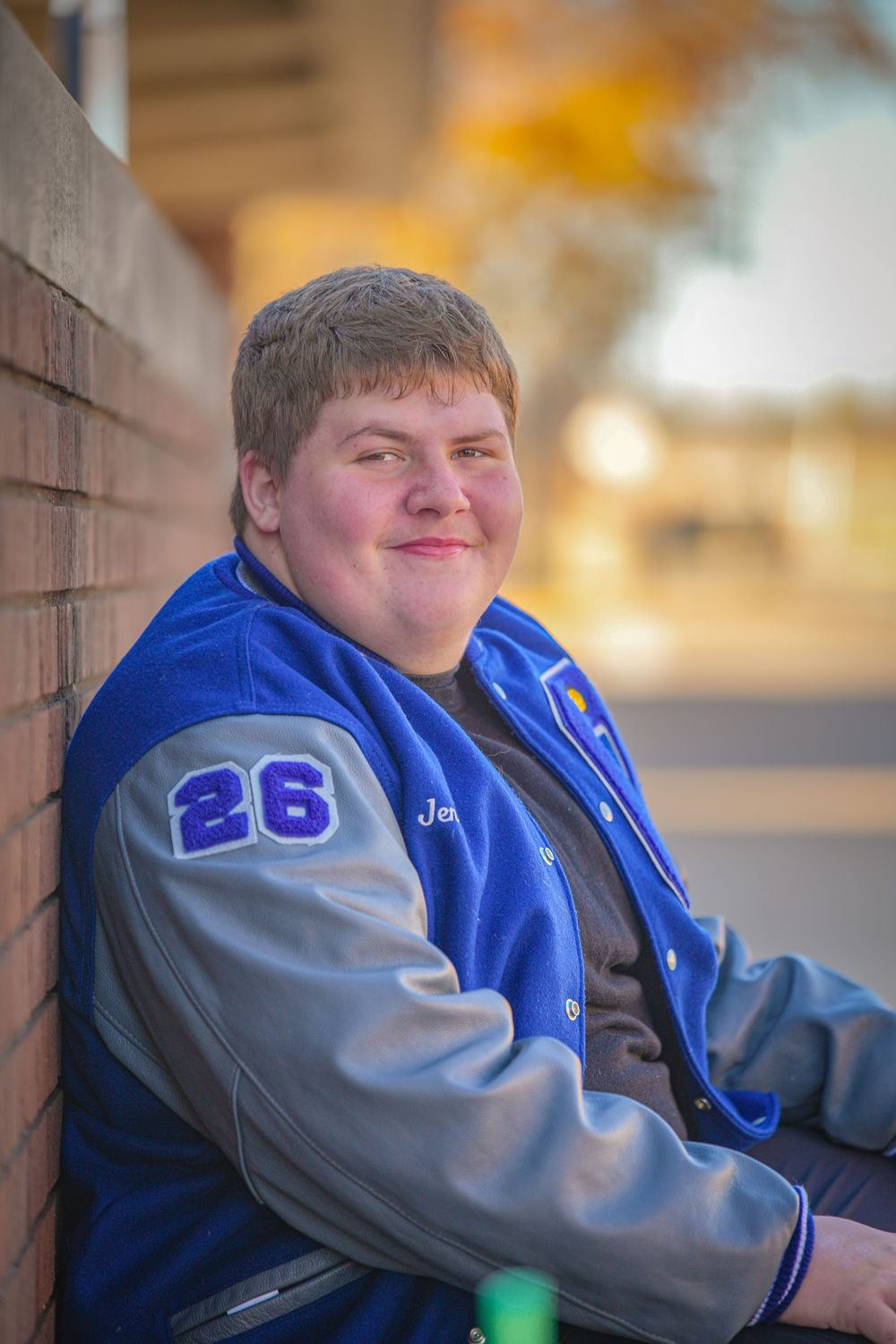 A person wearing a blue and gray varsity jacket sits on a bench in a series of similar poses.