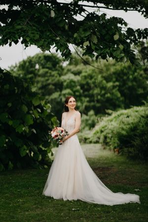 Ethereal wedding gown with flowing train photographed in lush garden setting.