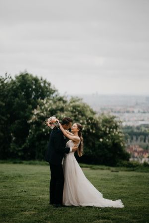 Joyful wedding moment captured against scenic hilltop landscape.