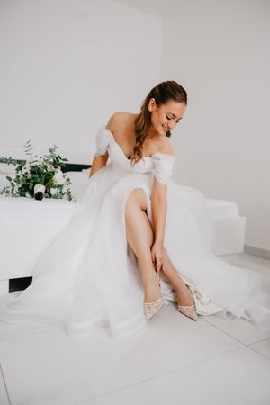 A series of elegant bridal detail shots featuring a white wedding gown and delicate shoes on a light background.