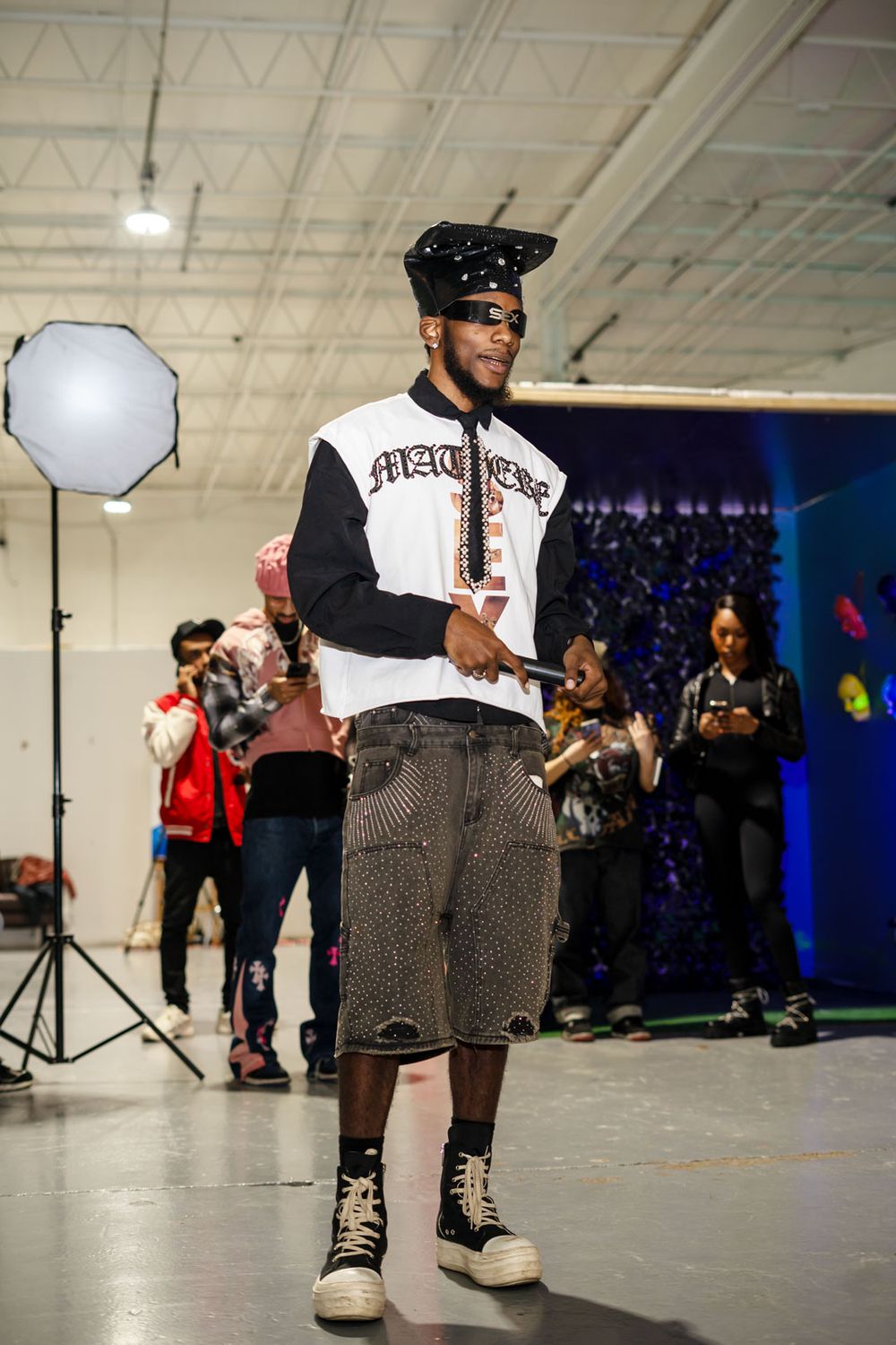 Behind the scenes photo shoot with bright studio lighting and octabox showing person in streetwear and baseball cap.