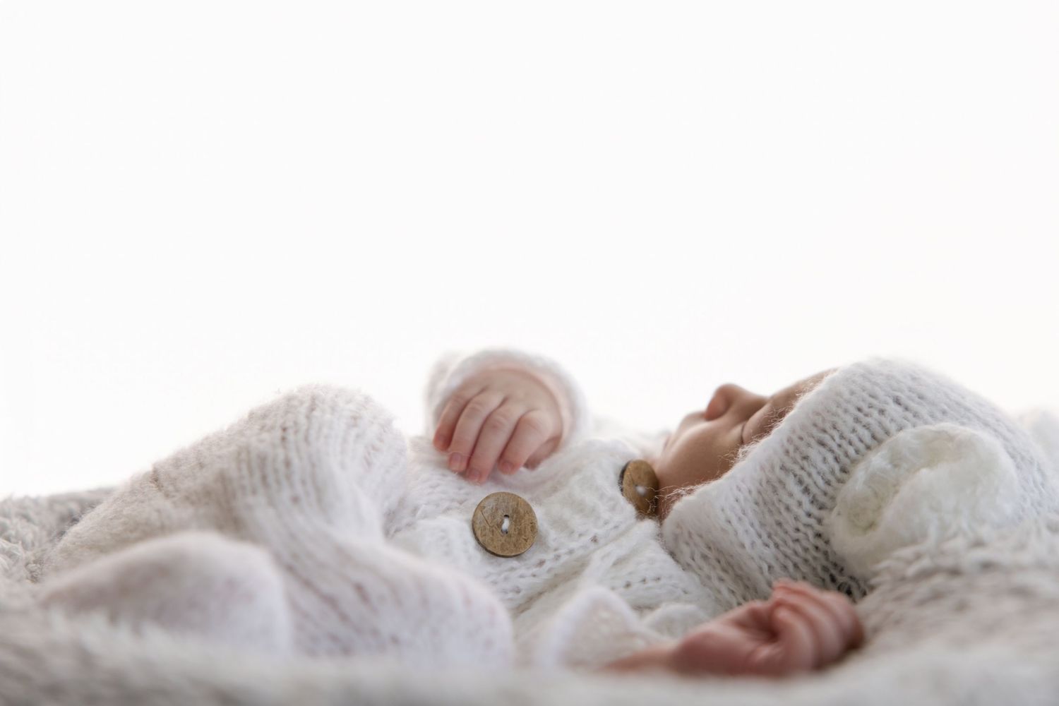 Salt Lake City Family Photographer - A loving moment between parent and newborn baby wrapped in white fabric while sitting on cozy chair.
