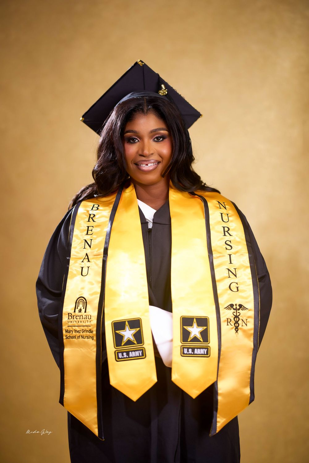 Graduate wearing black cap and gown with gold stoles displaying military honors and academic achievements.