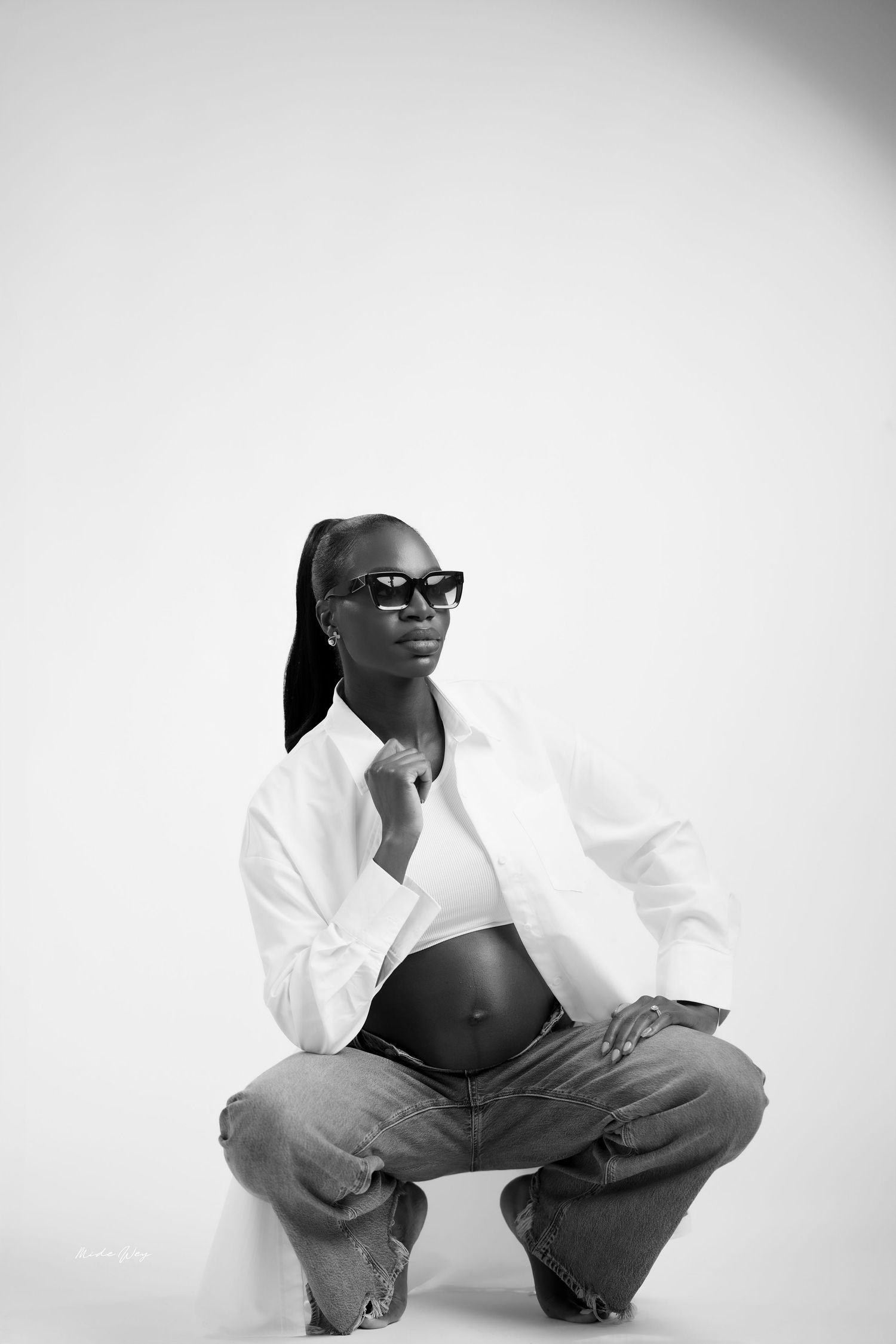 Black and white fashion photo series showing artistic poses against a white background wearing sunglasses and white shirt.