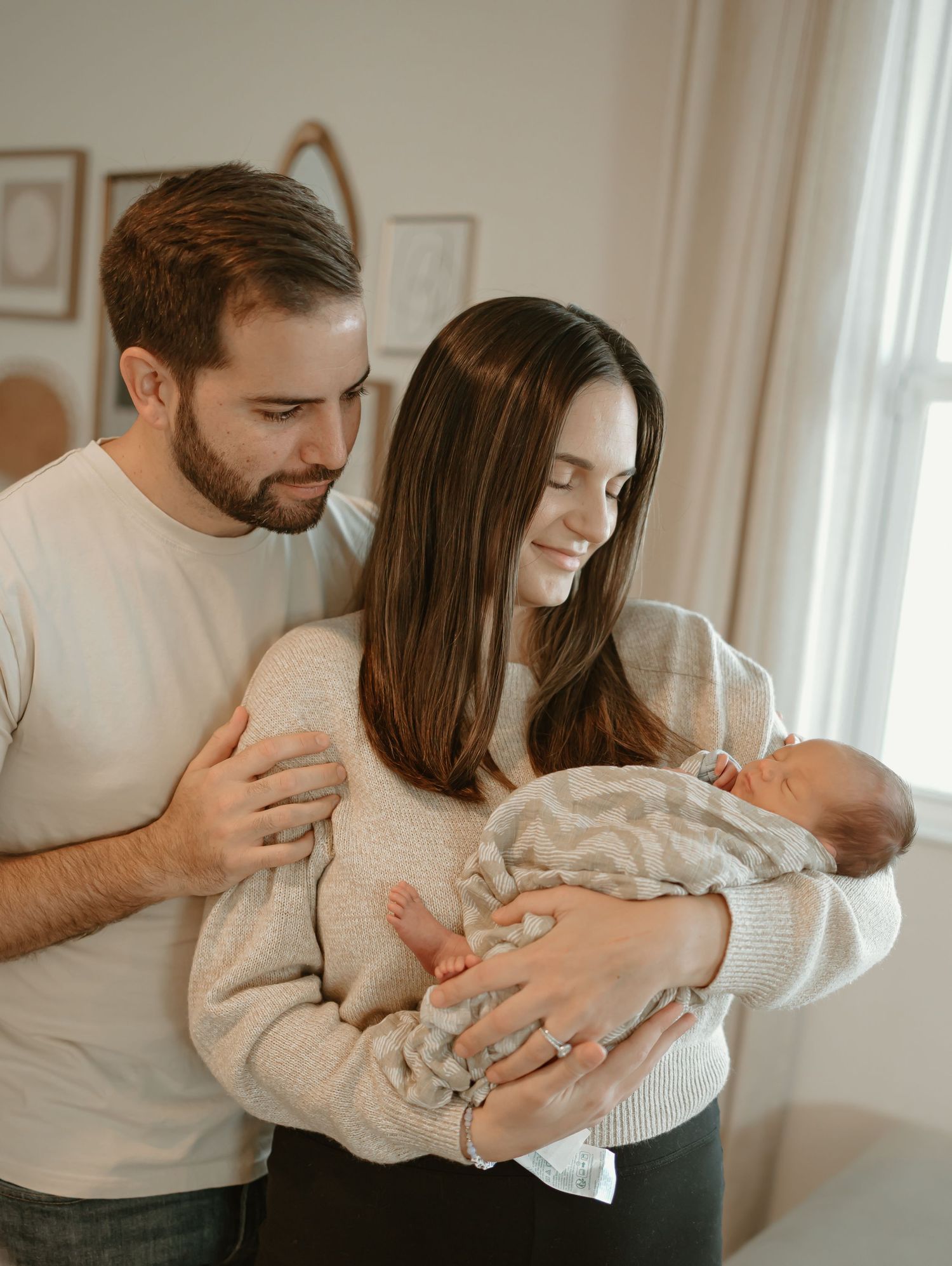 A tender moment between parents and their newborn baby in a bright, cozy room.
