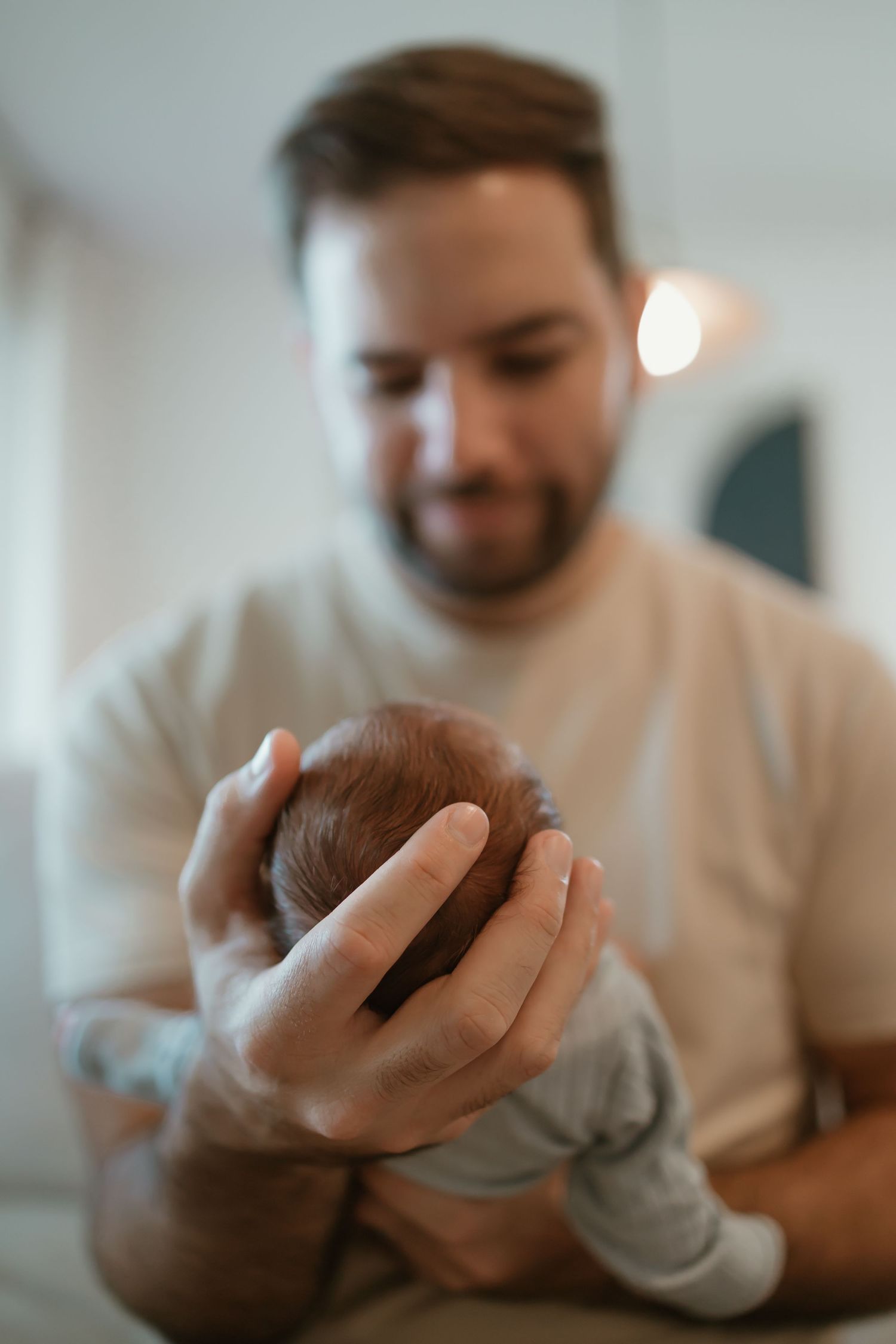 A newborn baby being gently cradled in someone's arms wearing a gray sweater.
