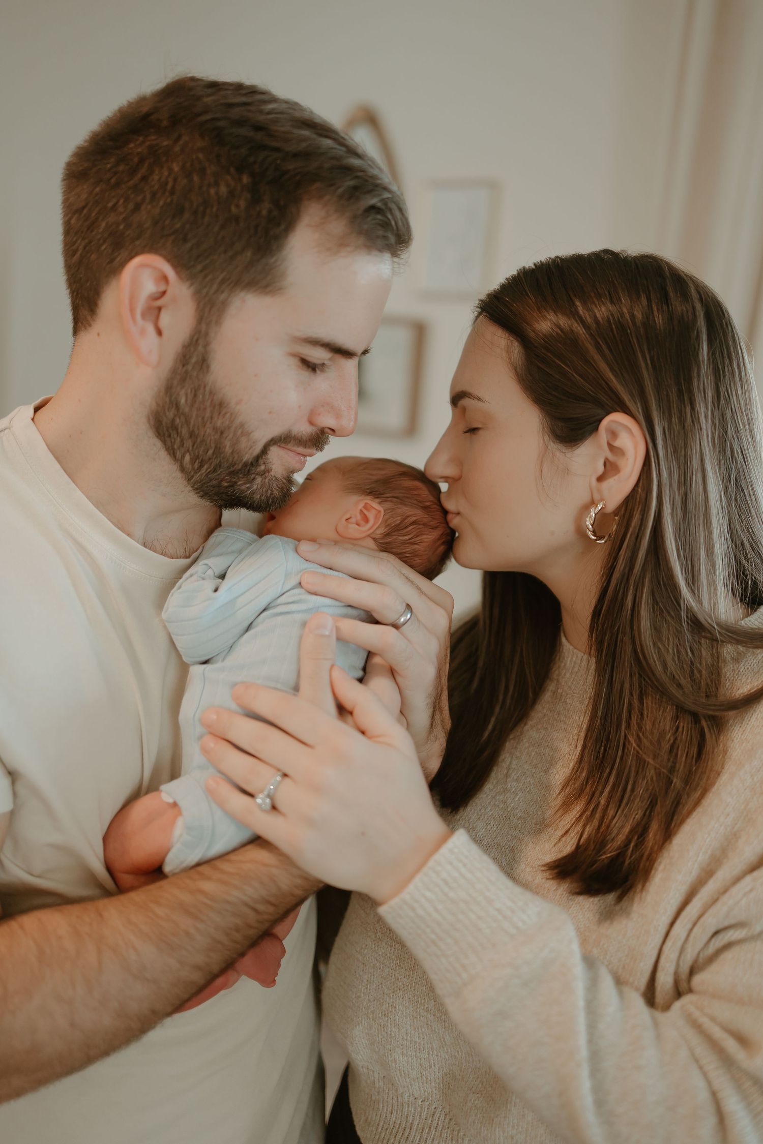An intimate family moment with a newborn baby being held and kissed by parents.