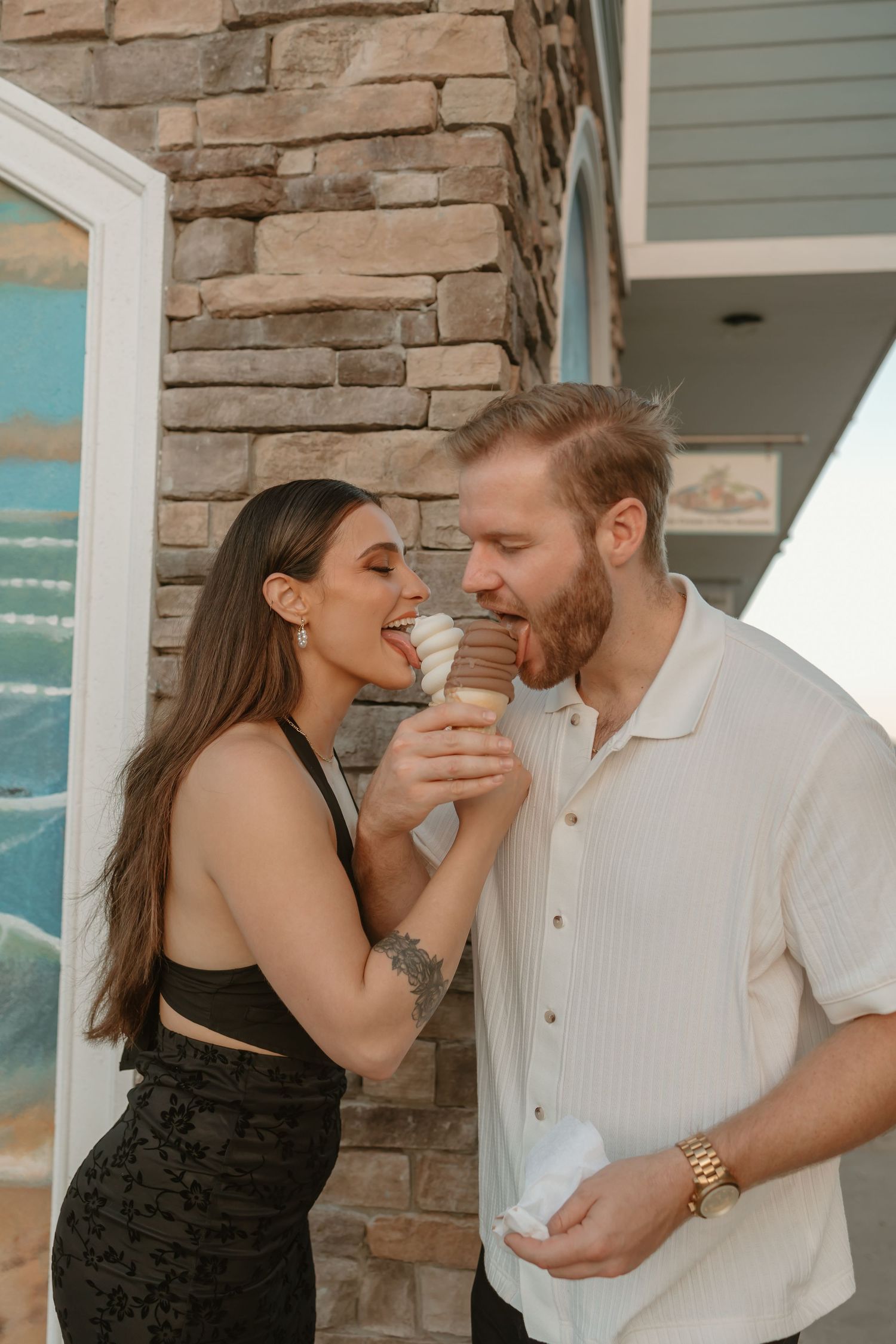 Playful couple sharing a moment against a stone wall exterior.