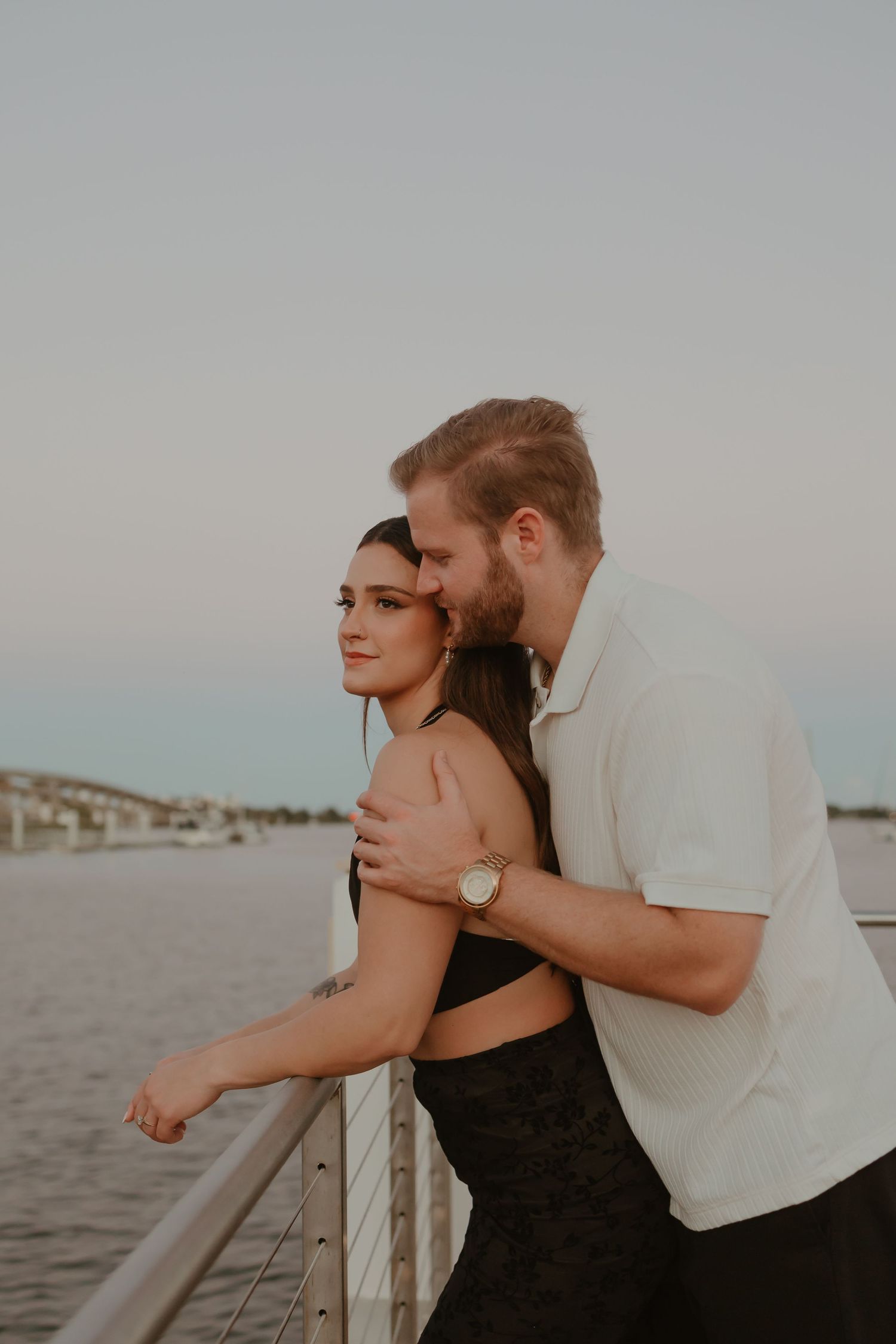 Romantic couple embracing on a waterfront deck at sunset.