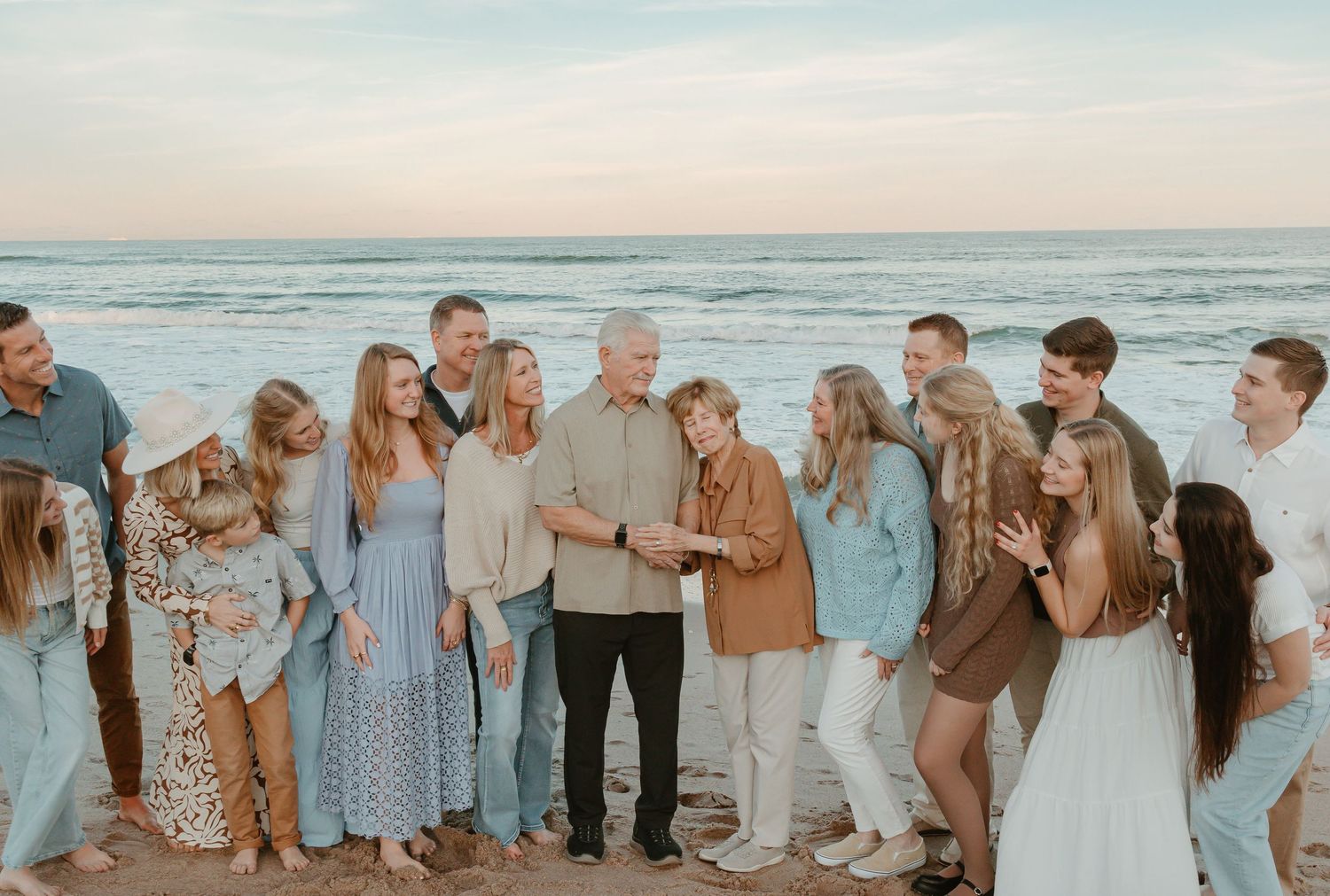 Family members lined up along beach shore during sunset photo session.