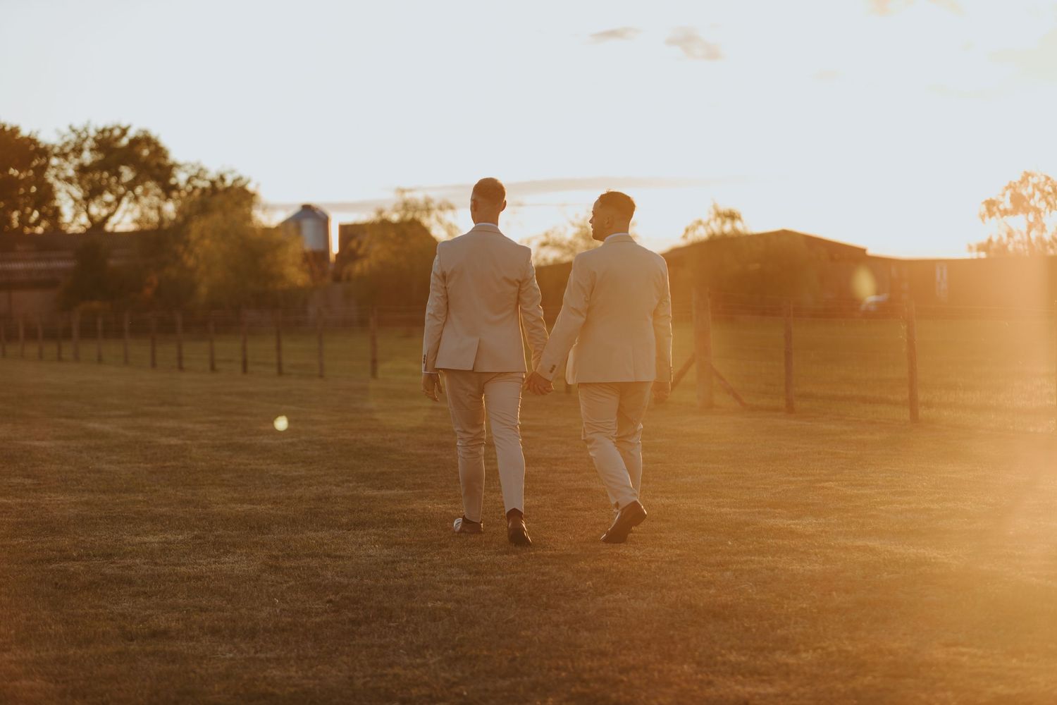 People walking on a path during golden hour sunset with soft glowing sunlight creating a warm atmospheric scene.