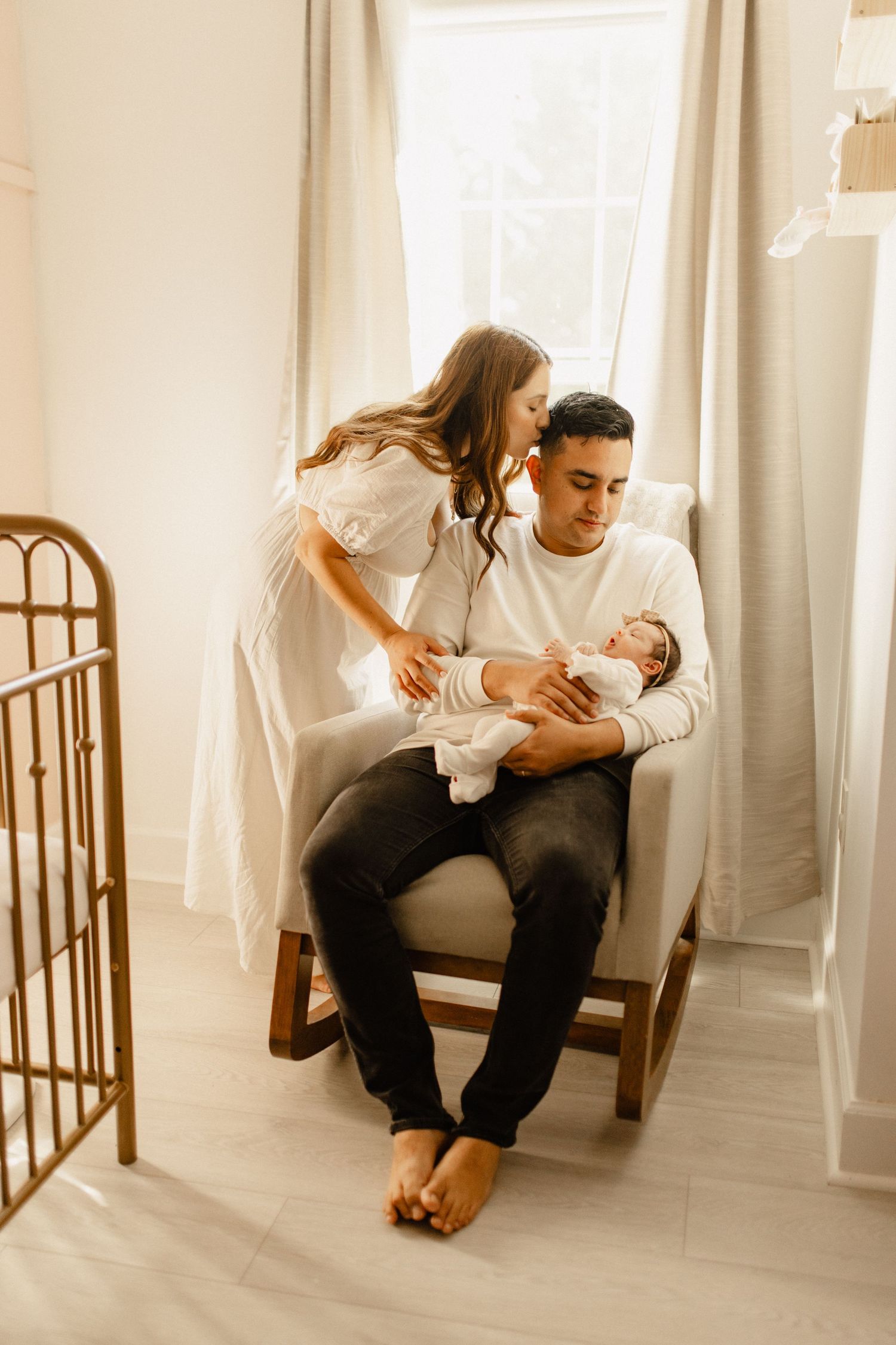 A sweet family moment with a newborn baby in a cozy nursery with natural lighting.