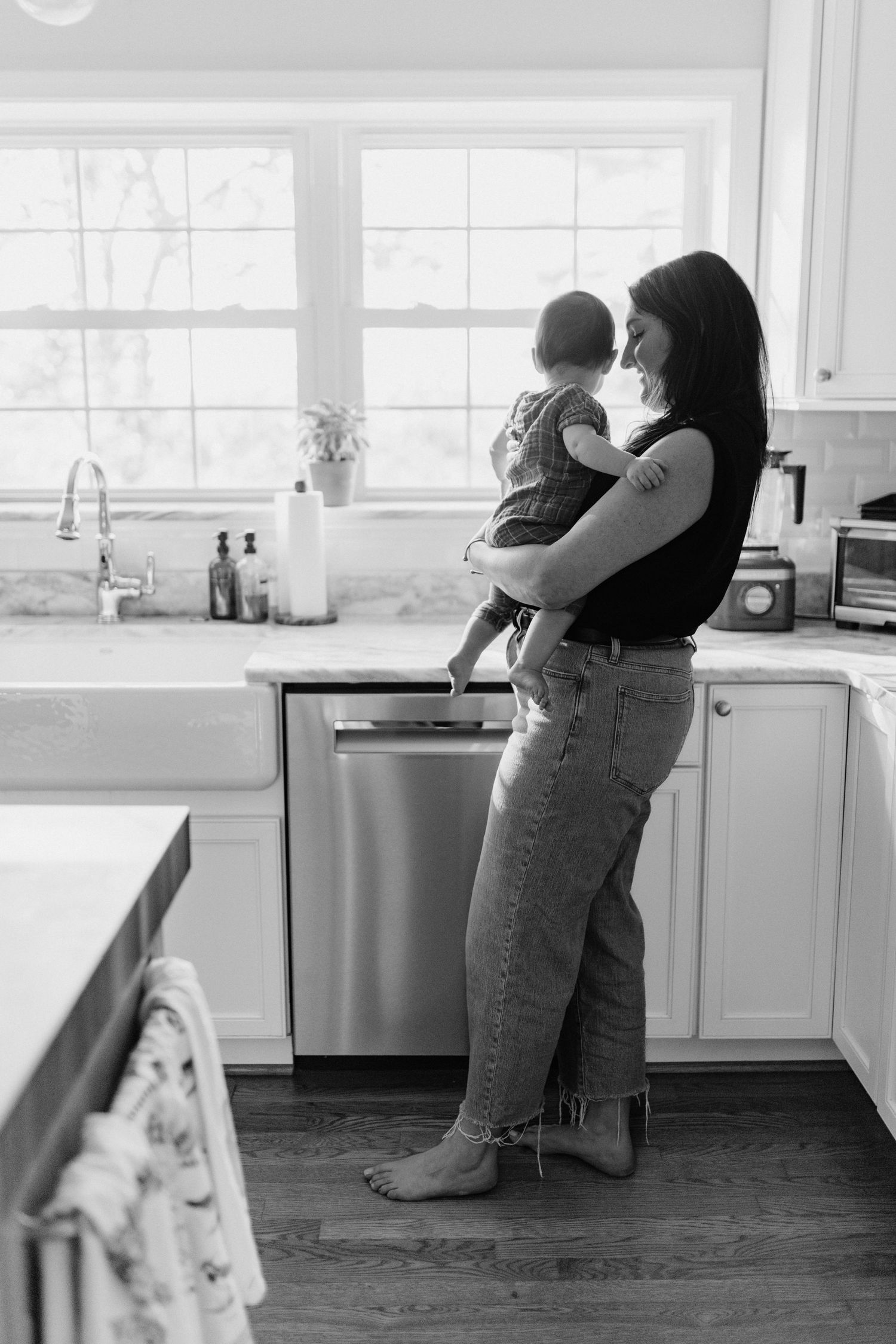 A tender moment shared between parent and child in a sunlit white kitchen interior.