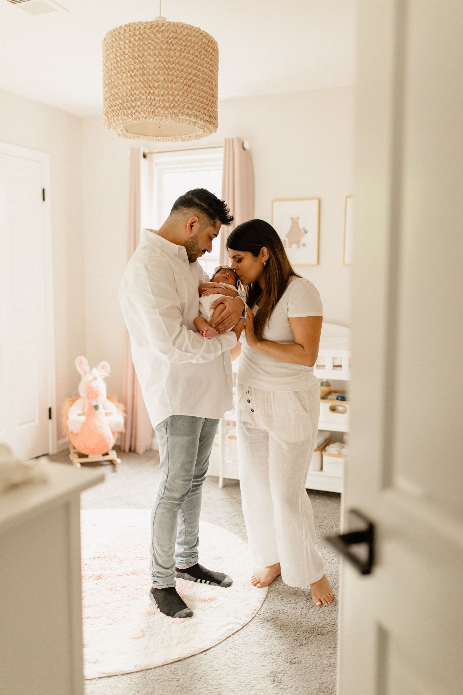 An intimate family moment with a newborn in a nursery decorated with soft pink accents.