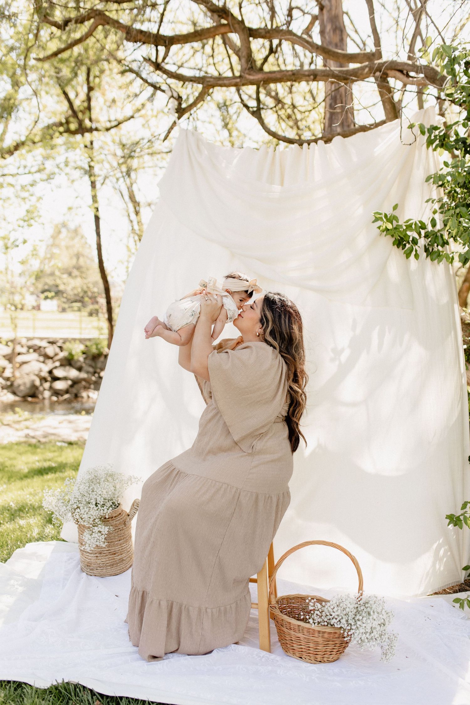 An outdoor baby photoshoot setup with white backdrop, baskets and baby's breath flowers.