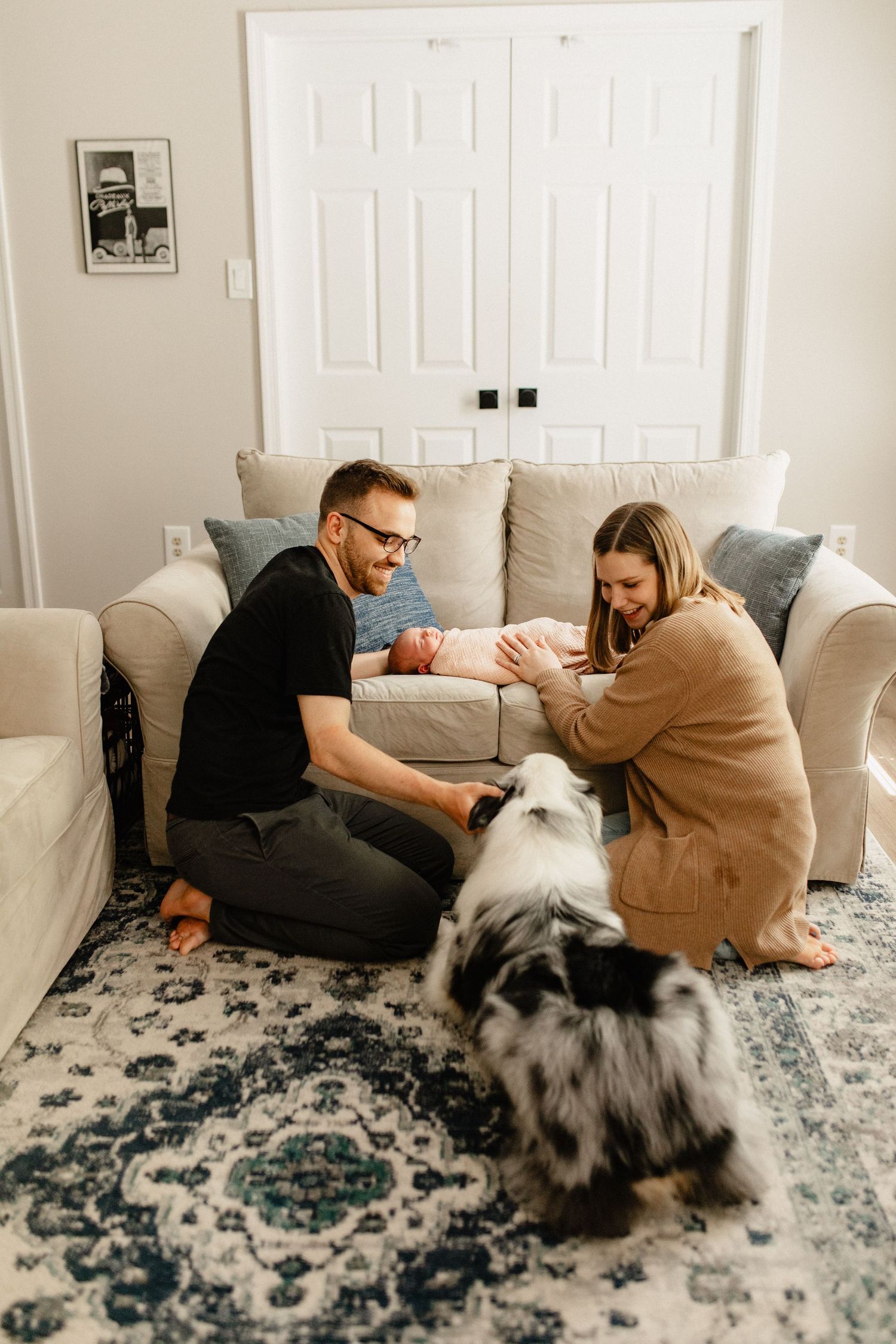 A family sharing a tender moment on their living room couch with their pets nearby.