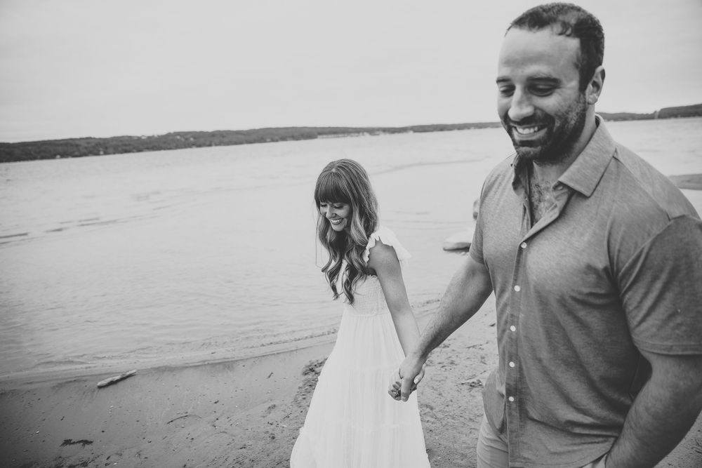 Black and white photos of a couple sharing intimate moments on a sandy beach.