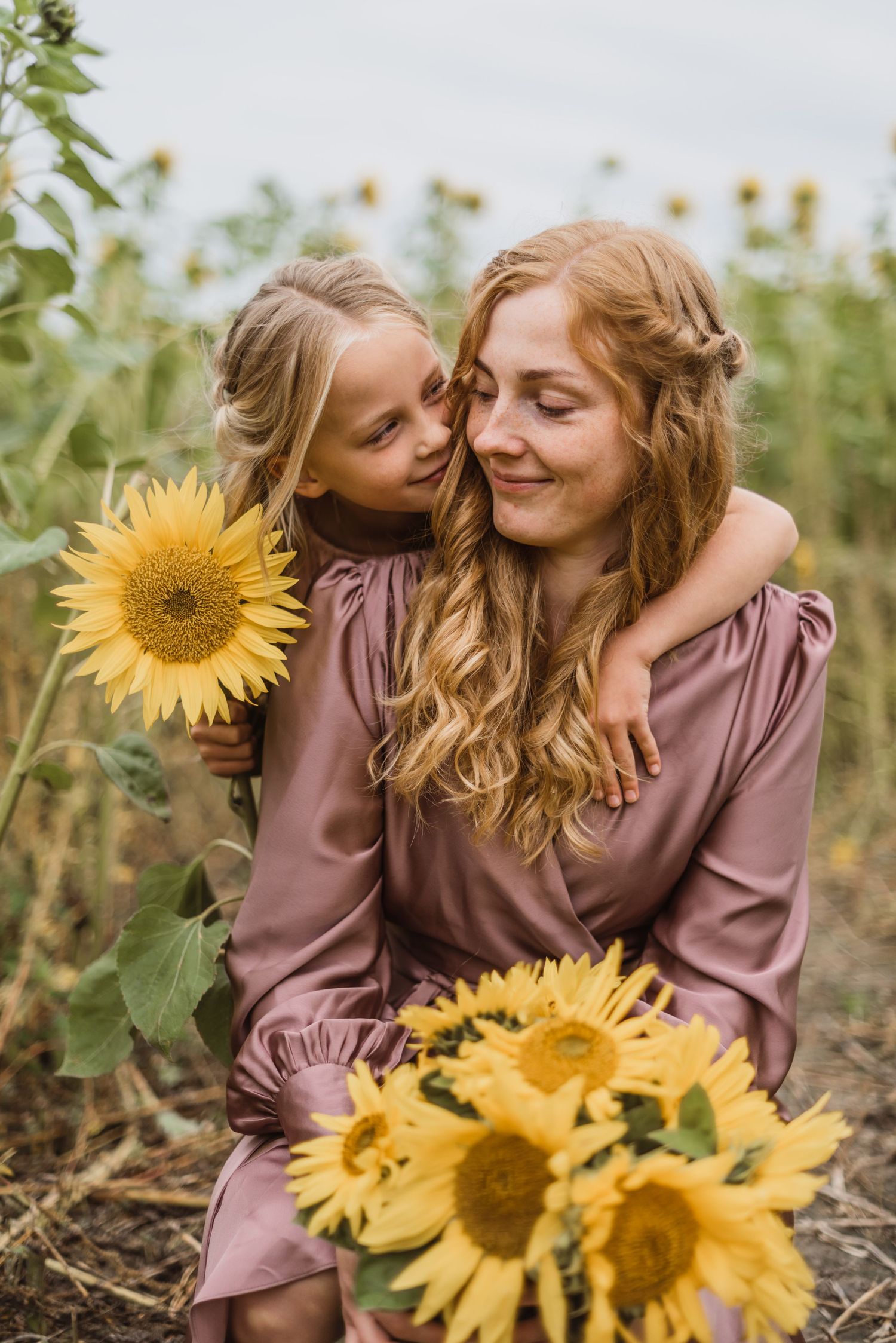 A touching moment between two people in a sunflower field during golden hour.