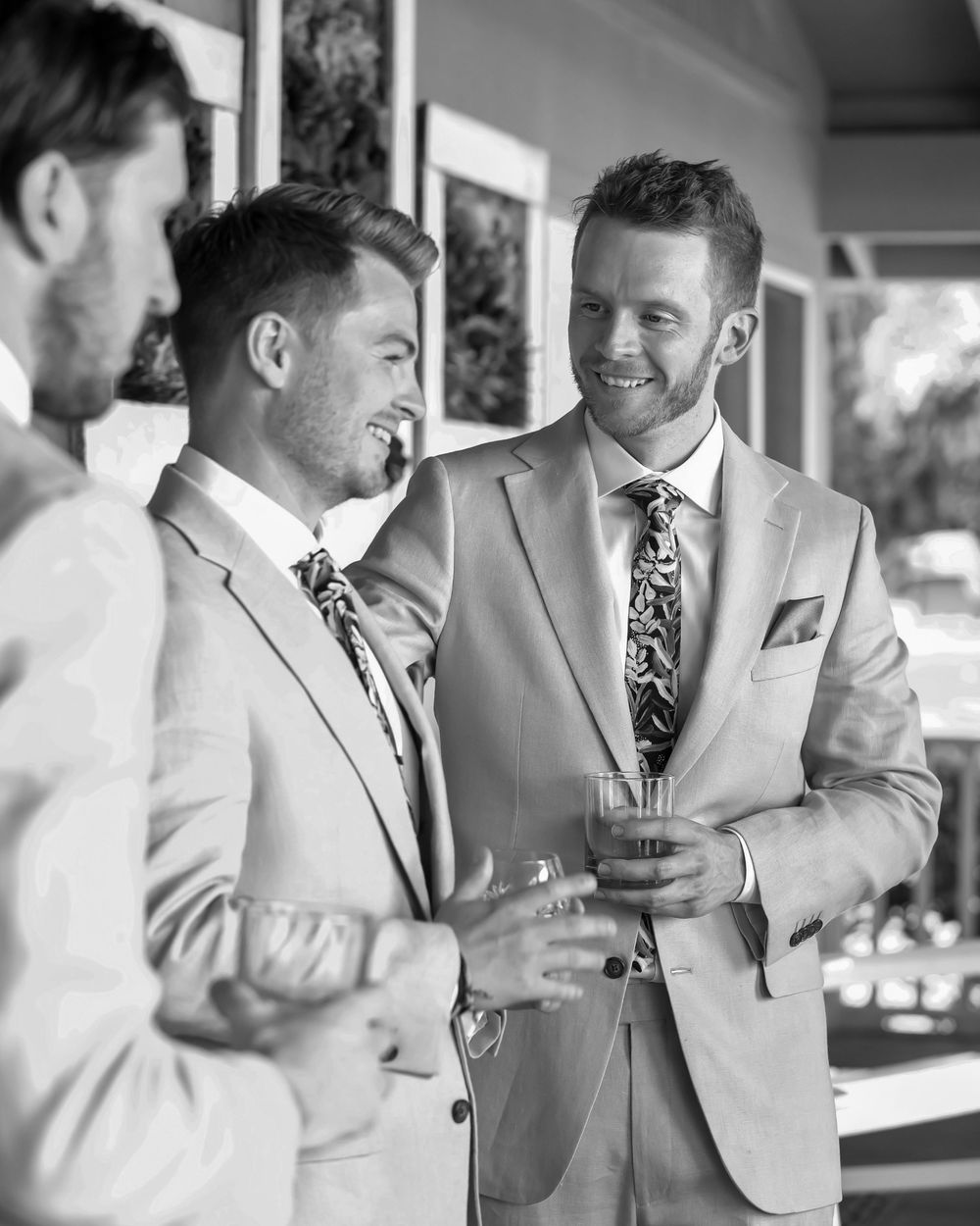 Two men in suits sharing a laugh and conversational moment at a formal event.
