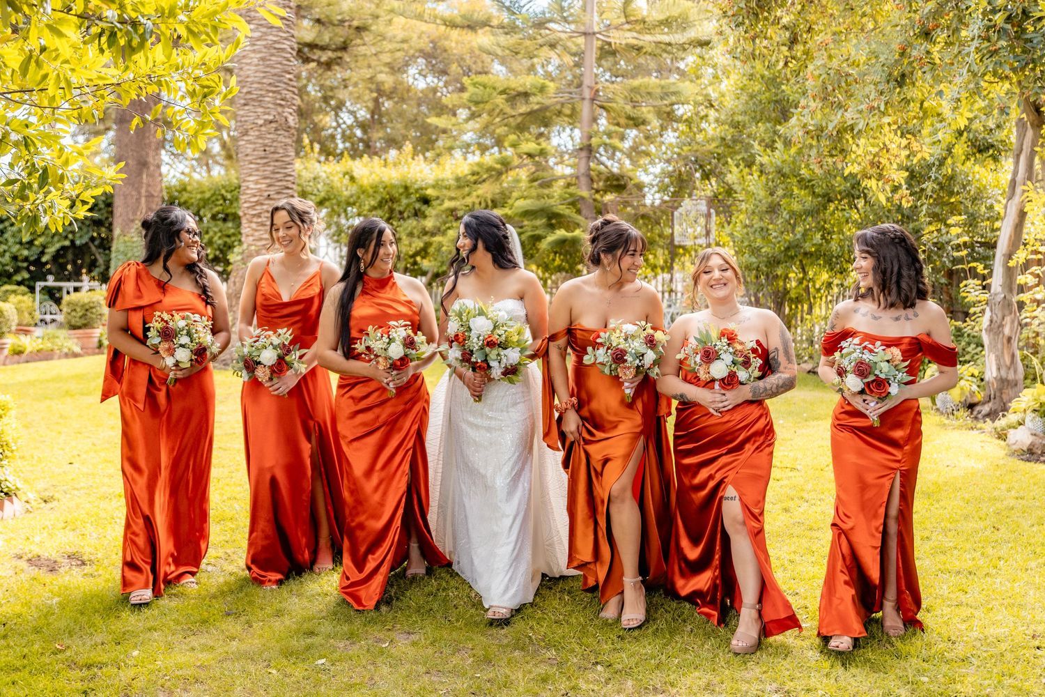 Mother helps bride with final dress adjustments in sunlit room before wedding ceremony.
